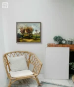 Tablou cu peisaj de toamna pictat manual, pe un perete alb, langa un fotoliu din ratan