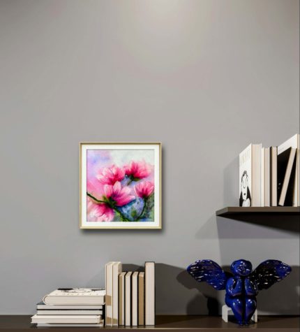 Tablou Magnolii cu paspartu, pe un perete gri, deasupra unor carti si a unui decor albastru