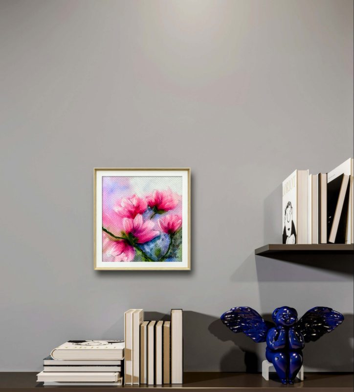Tablou Magnolii cu paspartu, pe un perete gri, deasupra unor carti si a unui decor albastru
