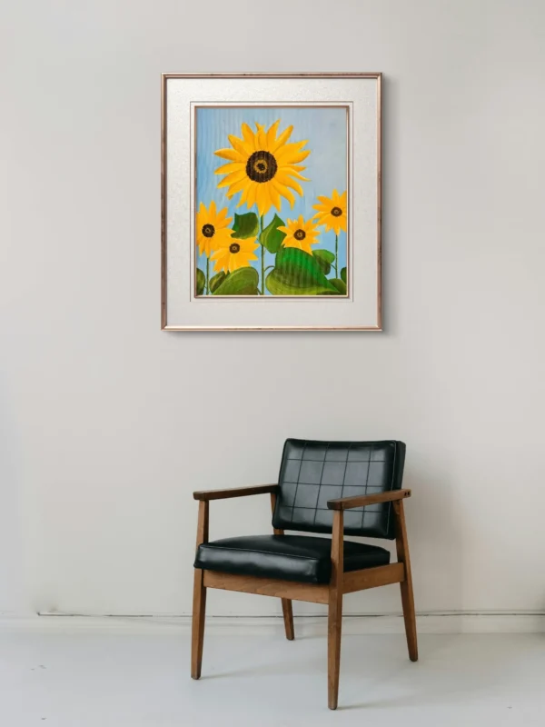 Tablou canvas Floarea Soarelui pe un perete alb, deasupra unui fotoliu negru