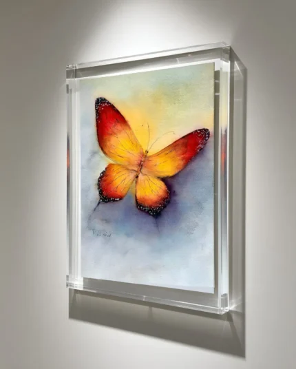 Tablou cu fluture portocaliu pe perete gri, in lumina de galerie, vazut din lateral